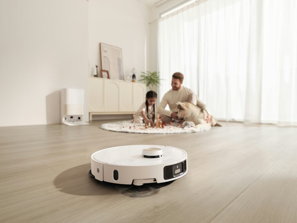 Robotstøvsuger gør rent i en stue, mens familien slapper af